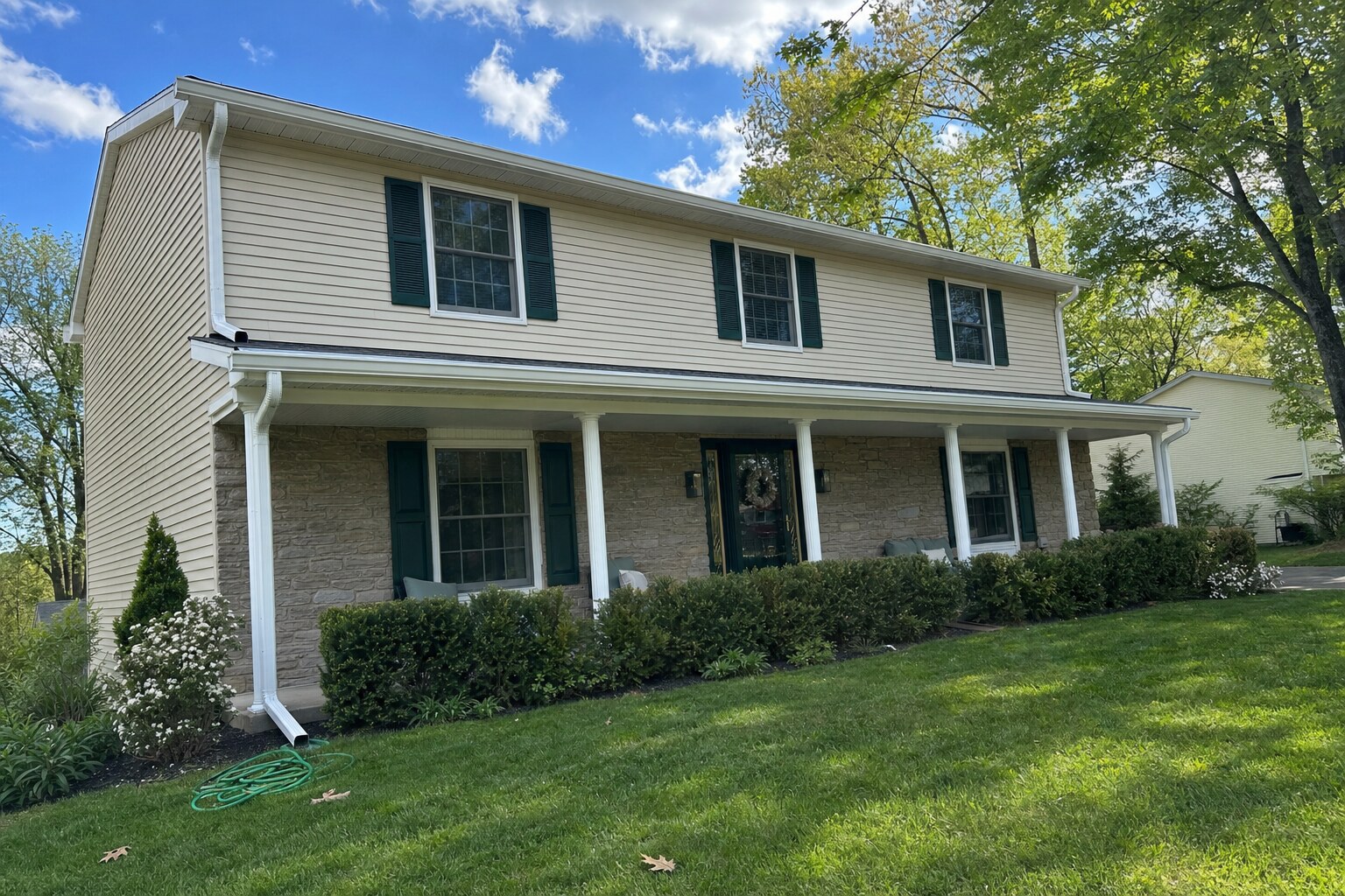 Full eave of a Colonial home with freshly brightened white aluminum gutters running the entire length