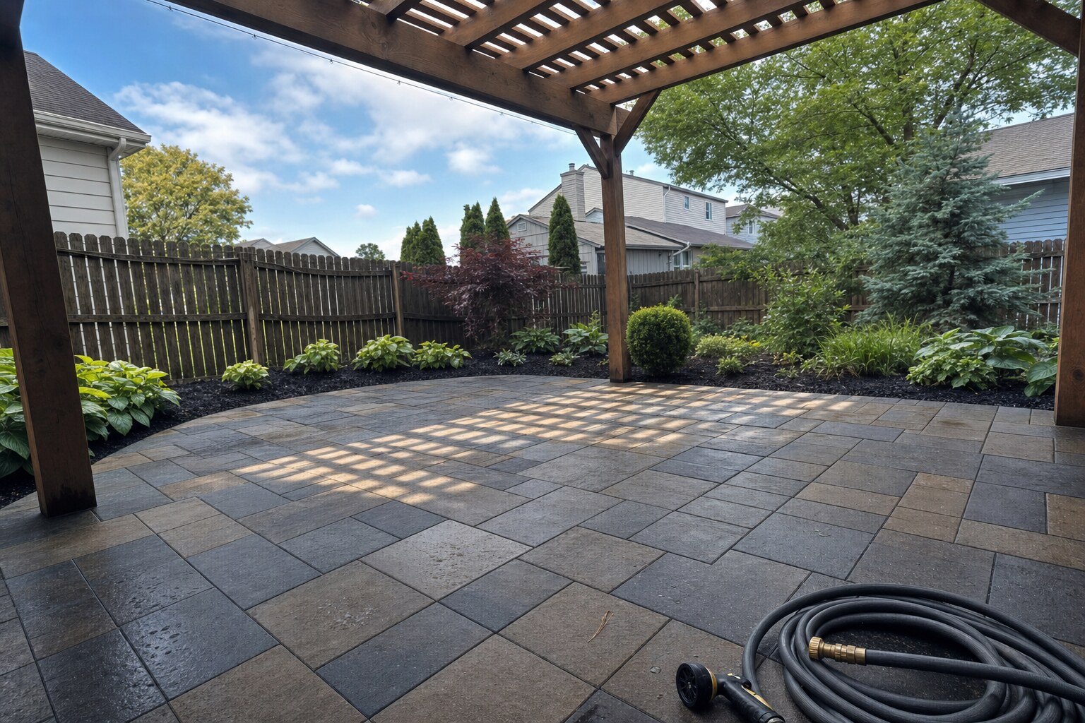 Charcoal-and-tan flagstone paver patio, freshly cleaned under pergola light