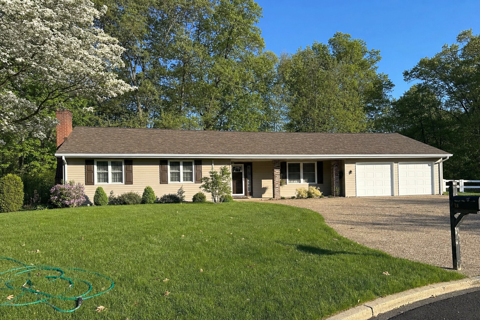 Single-story ranch home with a long low-pitched warm-brown asphalt shingle roof, freshly soft-washed