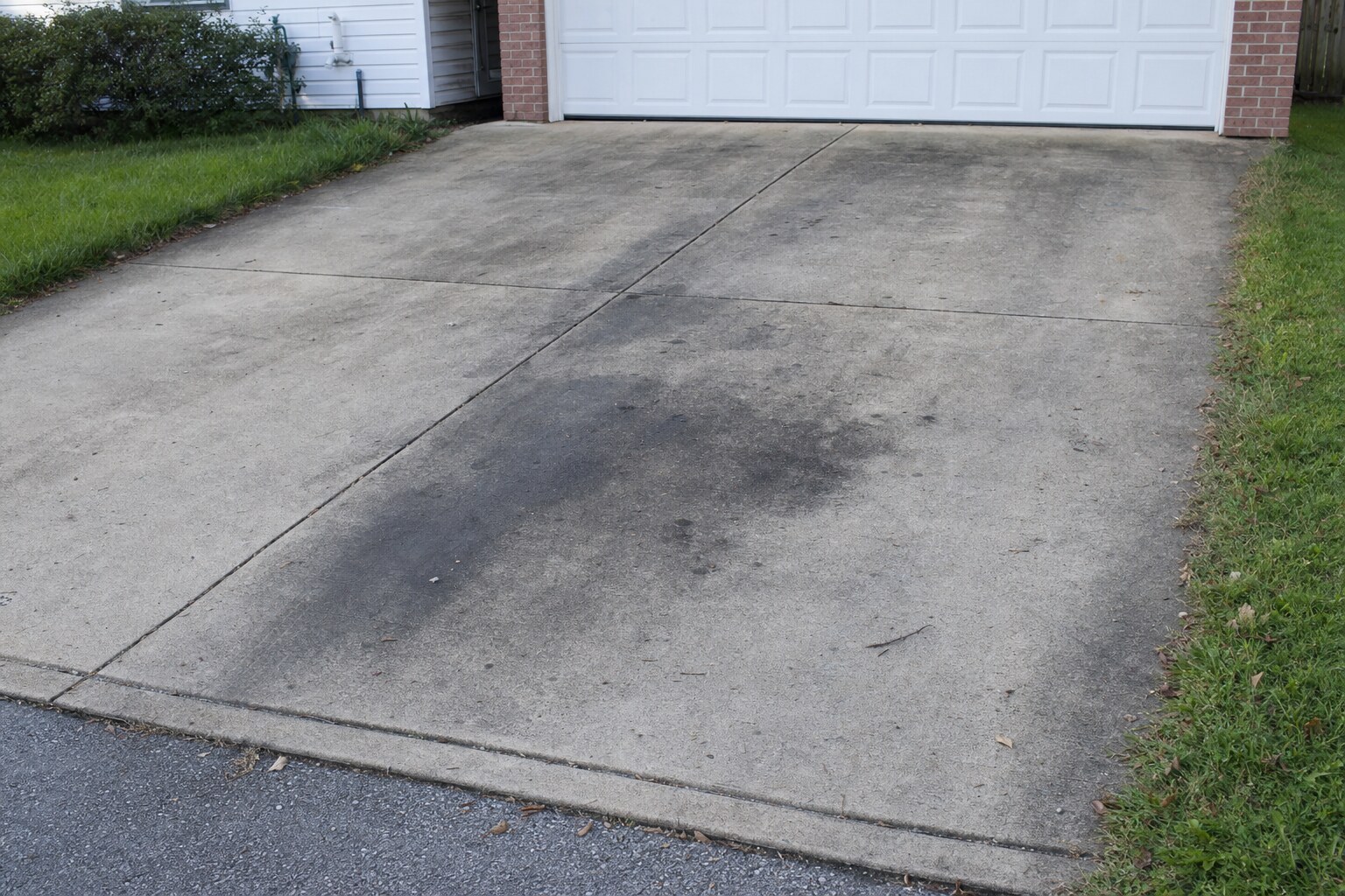 Concrete driveway with heavy oil stains and tire marks
