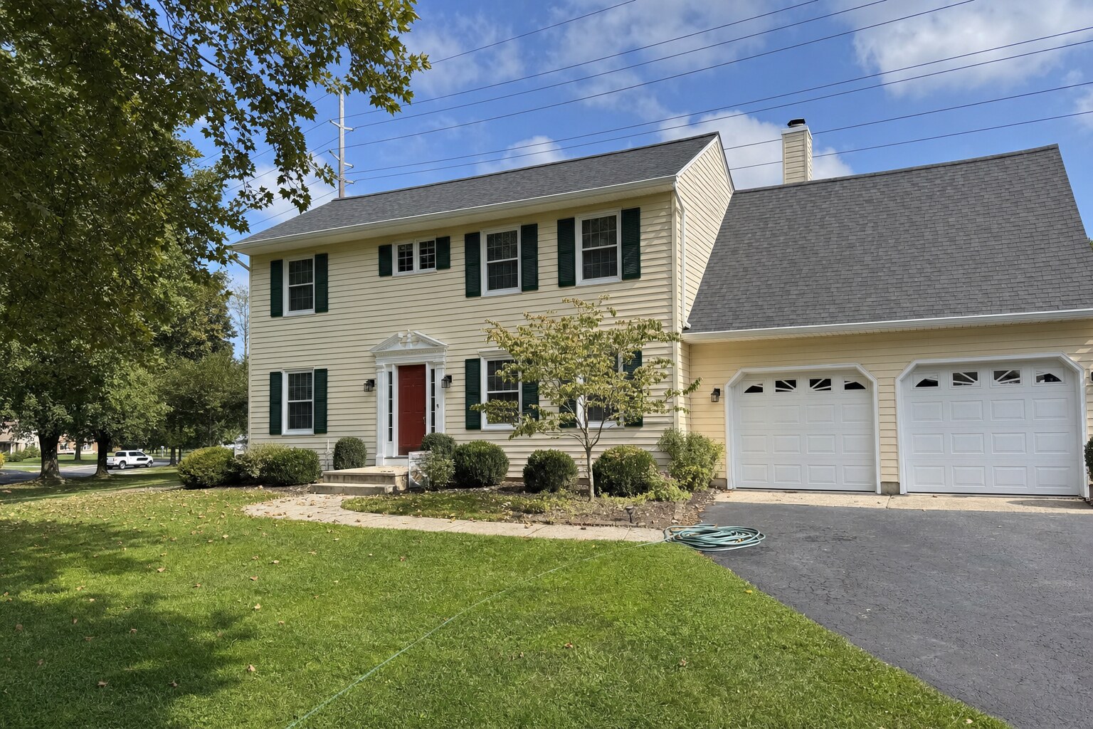 Two-story home with cream vinyl siding, freshly cleaned with low-pressure soft washing